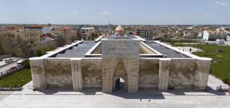 Frontal view of a medieval caravanserai with imposing archway in urban surroundings, aerial view,