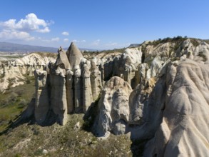 Impressive rock formations under a blue sky in a dry, rocky landscape, aerial view, Love Valley,