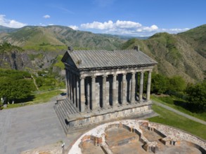 Ancient temple with columns in a green mountain landscape under a blue sky, aerial view, Temple of