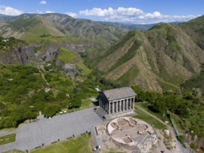 Aerial view of an ancient temple in the middle of a green mountain landscape under a cloudy sky,