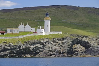 Lighthouse and building on green coastal landscape above the sea, Stevenson family, Noss, Shetland
