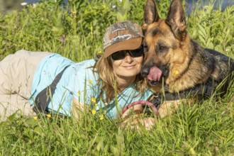 Woman and her German Shepherd lying in the grass, Sunny day, Gaspesie Region, Province of Quebec,