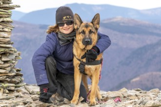 Woman and her German Shepherd sitting on a mountain top, Gaspesie Region, Province of Quebec,