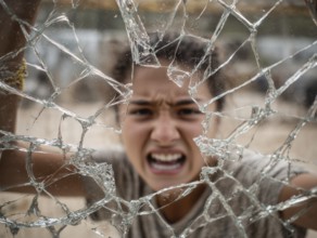 Ein Teenager schreit wütend durch eine kaputte Fensterscheibe, Aggressives Verhalten, Psychologie,