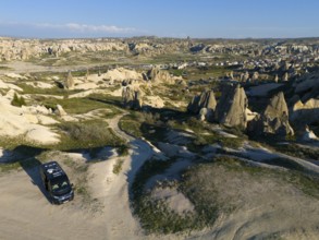 Expansive rocky landscape with a parked van and view of Cappadocia, aerial view, camper, motorhome,