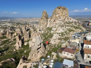 Combination of rock formations and modern buildings under a blue sky in a Turkish town, aerial