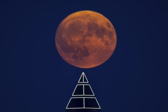 The full moon passes over the top of the Messeturm in Frankfurt am Main, Frankfurt am Main, Hesse,