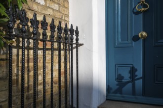 Blue door with brass-coloured door handle and wrought-iron grille in the sunlight, Kensington,
