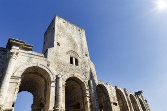 Roman amphitheatre in front of a blue sky, sunbeams, Arles, Provence, France