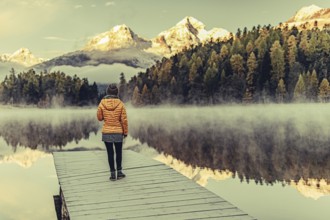 Young woman at Lake Staz near Sankt Moritz in the Engadine in Switzerland. Morning atmosphere with
