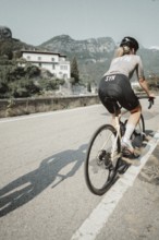 Young woman riding a racing bike on Lake Garda. Sunny weather and dolce vita