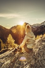 Woman sitting thoughtfully at a feslen at autumn atmosphere during sunset in the Swiss Alps in the