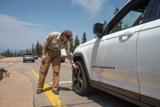 Colorado Springs, Colorado - A Pikes Peak ranger checks the temperature of brakes on a car