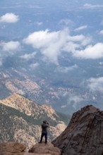Colorado Springs, Colorado - A man takes photos from the rocks just below the summit of Pikes Peak,