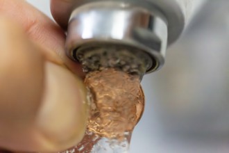 Symbolic image of a water cent: A cent piece under a running tap