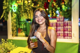 Customer savoring a mojito cocktail at a bustling night market, surrounded by colorful lights and