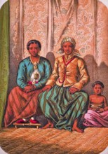 Seated Javanese family with father, mother and child, traditional clothing, headscarf, jacket, long