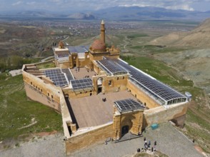 View of a large, well-preserved fortress with a dome in the background of an open landscape, aerial