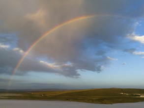 A rainbow stretches across a wide landscape under a colourful sky, aerial view, salt lake, Tuz