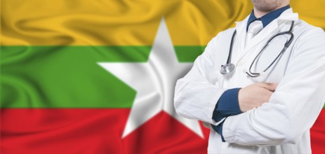 Myanmar healthcare concept. Male doctor on Myanmar flag. Doctor with crossed arms on Myanmar flag