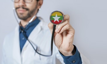 Doctor holding stethoscope with Myanmar flag. Myanmar health and care concept, Myanmar flag on