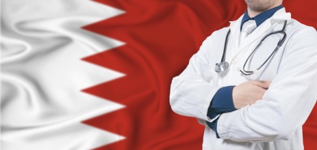 Bahrain healthcare concept. Male doctor on Bahrain flag. Doctor with crossed arms on Bahrain flag