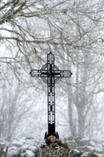 A beautiful wayside cross stands tall in winter with snow blanketing the landscape of the Aubrac