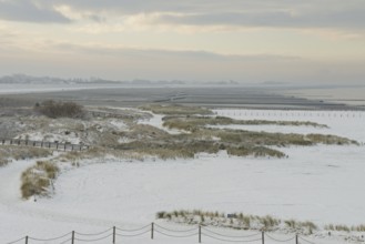 View over the snow-covered dune landscape of Norddeich, Wadden Sea at low tide, North Sea, Lower