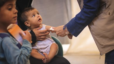 A doctor examines children's malnutrition inside a refugee camp