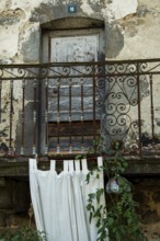 Located in an antique stone structure, this rustic balcony features an ornate railing, flowing