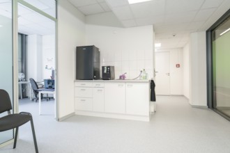 Modern kitchenette in the office with white cupboards and appliances, Care Connect, vaccination