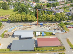 Crane over a construction site in a village landscape with many houses, car park construction,