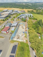 Crane near a construction site with surrounding greenery and buildings, car park construction,