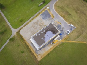 Aerial view of a construction site area with vehicles and a crane next to a partially completed
