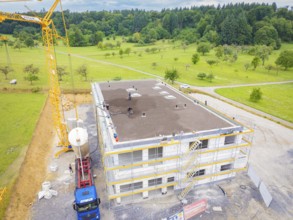 Construction site with a building under construction and a crane on a field, green roof, house