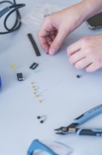 Hands working with small electronic components and tools on a table