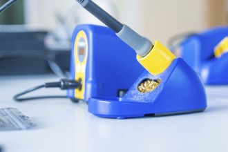 Blue soldering iron on a table with yellow accents and digital display