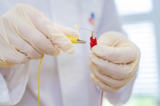 Researcher holds cable and LED in an electrical experiment in the laboratory, Battery Research,