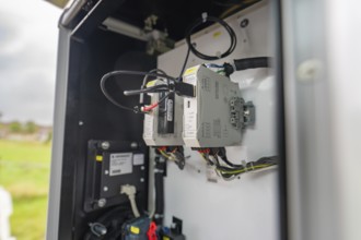 Open switch box with cables and background landscape outdoors, installation of a charging station