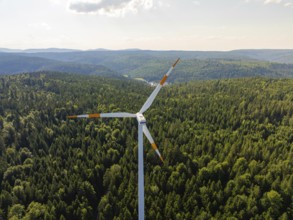 A single wind turbine in front of a vast wooded landscape under a bright sky, Simmersfeld, Black