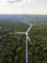 Close-up of a wind turbine in front of a vast wooded landscape under a blue sky, Simmersfeld, Black