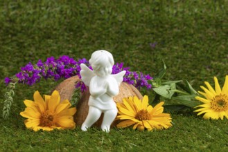 White angel figure with purple and yellow flowers on a green lawn