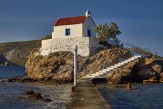 A small church with a red roof lies on a rock, accessible via steps and a pier, chapel, church,