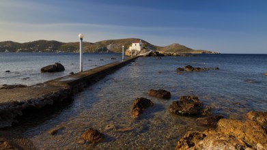 A stone pier leads to a church standing on a rock in the calm sea, chapel, church, Agios Isidoros,