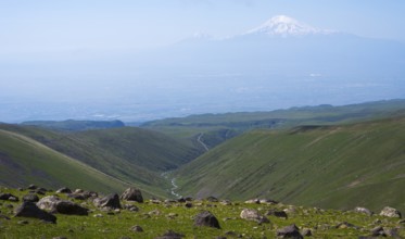 Extensive landscape with green valleys and snow-capped mountains on the horizon, view from Aragaz