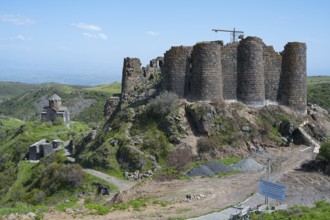 A historic fortress ruin rises above a green landscape under a blue sky, Amberd Fortress and Mother