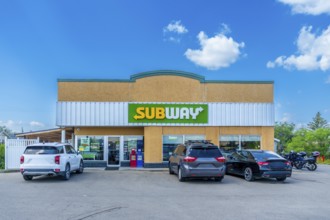 Sandwich restaurant chain with parking lot and cars parked in front on a sunny day with blue sky