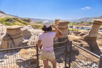 Young woman enjoying view of unique hoodoo rock formations at tourist attraction in drumheller,