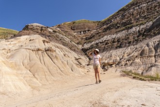 Female tourist walking through the arid and eroded landscape of drumheller valley in the canadian
