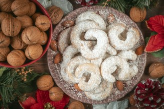 Vanilla croissants on a plate next to walnuts and Christmas decoration
